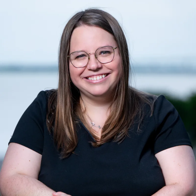 Portrait d’une femme souriante à lunettes, devant un fleuve