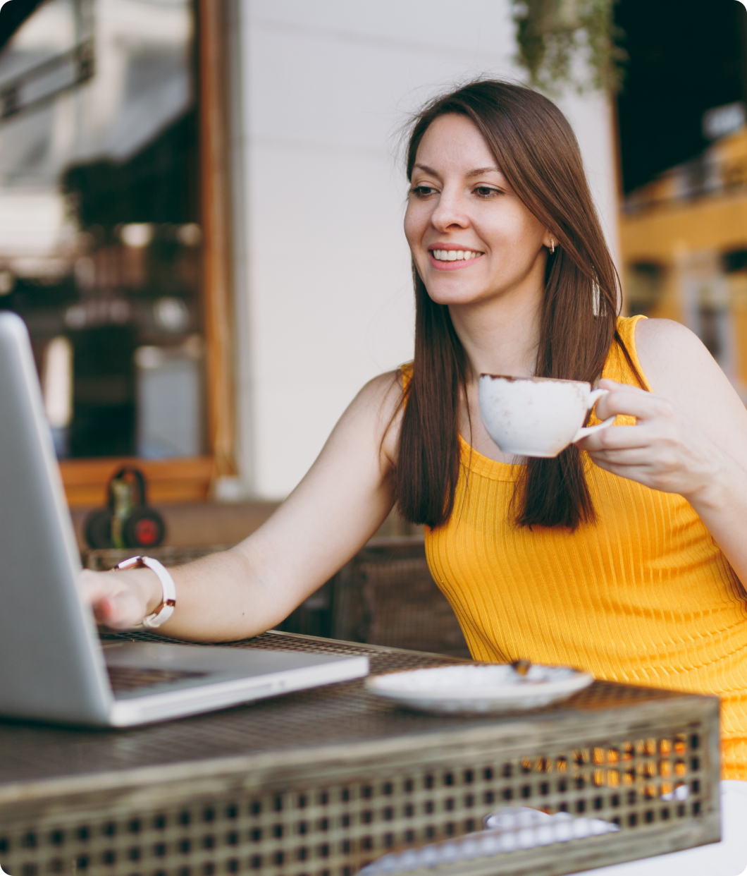 Personne tenant une tasse de café d'une main et tapant sur son clavier de l'autre